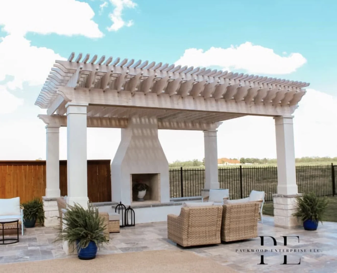 White pergola and outdoor fireplace beside a patio seating area